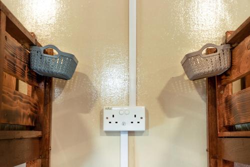 two baskets hanging on a wall next to a electrical outlet at Bunga Hostel Female Dorm in Pantai Cenang