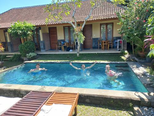 a group of people swimming in a swimming pool at Werkudara Guest House in Ubud