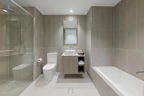 a bathroom with a toilet and a sink and a tub at Quest Watergardens in Taylors Lakes