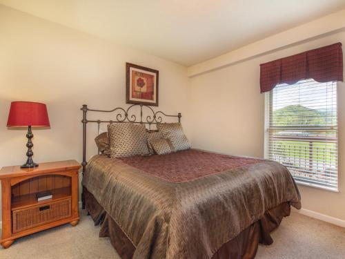 een slaapkamer met een bed, een tafel en een raam bij Riverside Dream Cedar Lodge 103 in Pigeon Forge