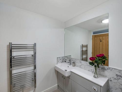 a white bathroom with a sink and a mirror at Orchard Barns in North Nibley