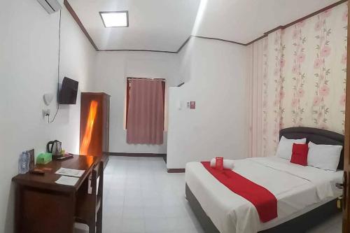 a hotel room with a bed and a desk and a bed sidx sidx at RedDoorz Plus @ Alun Alun Nganjuk in Nganjuk