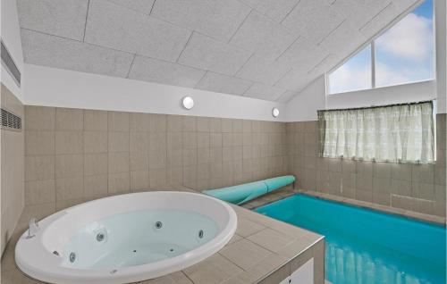 a bathroom with a tub and a swimming pool at 5 Bedroom Beautiful Home In Sydals in Høruphav