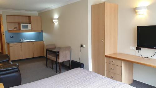 a hotel room with a bed and a desk and a kitchen at 97 Motel Moray in Dunedin
