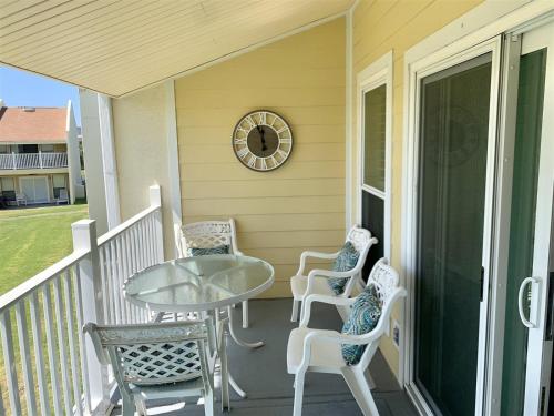a porch with chairs and a table and a clock at 10 H Two Bedroom Condo in Destin