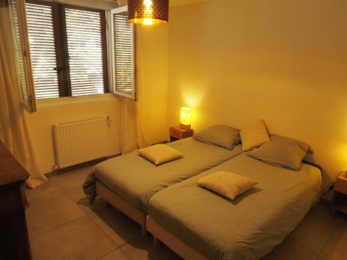 a bedroom with a bed with two pillows on it at Appartement en Provence-Lubéron - piscine et calme in Volx