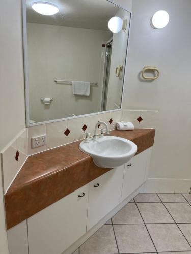 a bathroom with a sink and a mirror at Kings Row Apartments in Caloundra