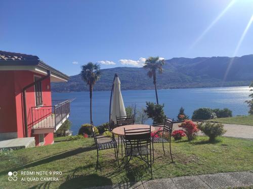 a table and chairs with a umbrella and a lake at Villetta Primavera in Verbania