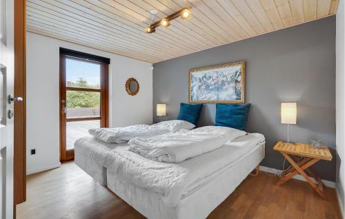 Schlafzimmer mit einem Bett mit weißer Bettwäsche und blauen Kissen in der Unterkunft Nice Home In Hals With 3 Bedrooms, Wifi And Outdoor Swimming Pool in Hals
