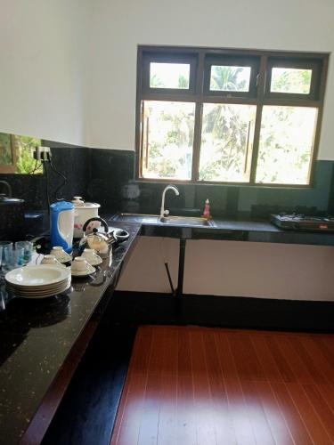 eine Küche mit einer Theke, einem Waschbecken und einem Fenster in der Unterkunft Ashi Galle Villa in Galle