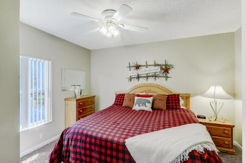 a bedroom with a bed with a plaid blanket and a ceiling fan at Lazy Bear Whispering Pines 111 in Pigeon Forge