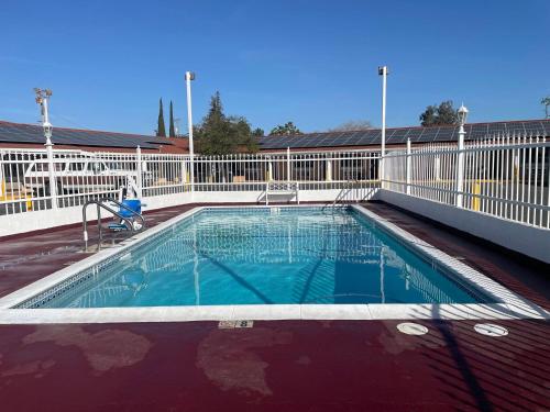 a large swimming pool with a white fence at Holiday Motel Oakdale in Oakdale