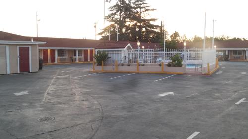 a parking lot in front of a building with a white fence at Holiday Motel Oakdale in Oakdale