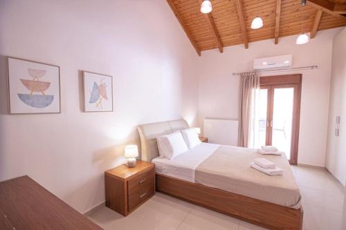 a bedroom with a bed with a night stand and a window at The Archanes Sapphire in Archanes