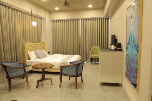 Apricot Motera في أحمد آباد: غرفة فندقية بسرير وطاولة وكراسي