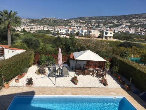 a swimming pool with a umbrella and a table and chairs at Villa Oasis Peyia near Coral Bay in Peyia
