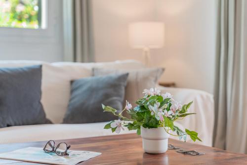 a vase of flowers on a wooden table with a couch at Casa Mayor Strand Es Trenc 5 min in Sa Ràpita