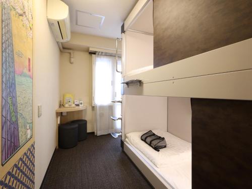 a small room with a bunk bed and a desk at Dormy Inn EXPRESS Asakusa in Tokyo