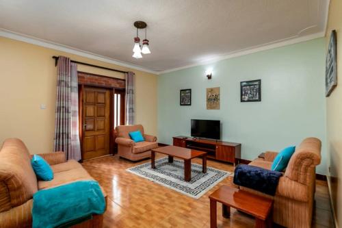 a living room with two couches and a tv at Victoria Breeze Suites, Entebbe in Entebbe