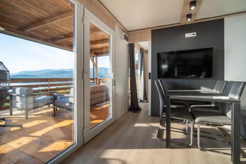 Zimmer mit einem Balkon mit einem Tisch und einem TV. in der Unterkunft Luxury Mobile home Zuzu Klenovica in Klenovica