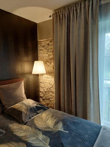 - une chambre avec un lit doté d'une lampe et d'une fenêtre dans l'établissement La chambre et le studio du château du golf de Bernalmont, à Liège
