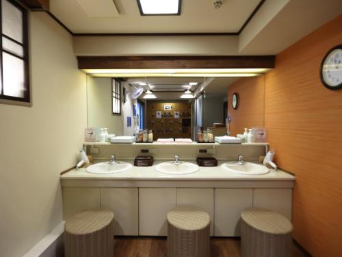 a public bathroom with three sinks and two stools at Dormy Inn EXPRESS Asakusa in Tokyo