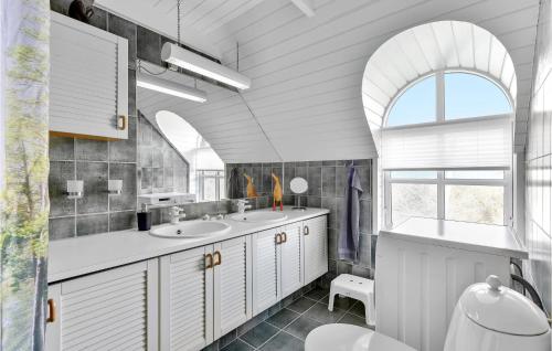 uma casa de banho com 2 lavatórios e uma janela arqueada em 3 Bedroom Beautiful Home In Ringkbing em Ringkøbing