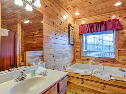 y baño de madera con bañera, lavamanos y bañera. en Apple Bear Lodge, 4 Bedrooms, Sleeps 18, Jacuzzis, Pool Table, Hot Tub en Gatlinburg