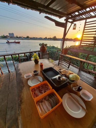 a table with food and a view of the water at Baan GoLite Ko Kret - บ้านโกไล้เกาะเกร็ด in Nonthaburi
