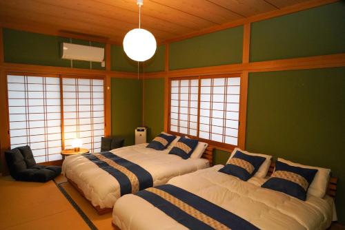 別府市にあるLiving CUBE Beppuの緑の壁と窓が特徴の客室で、ベッド2台が備わります。