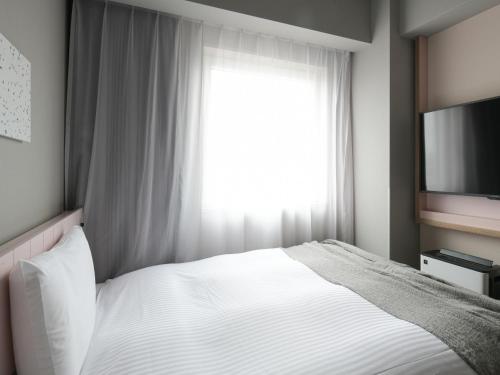 a bedroom with a white bed and a window at Vessel Inn Takadanobaba Station in Tokyo