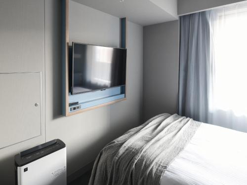 a bedroom with a bed and a tv on the wall at Vessel Inn Takadanobaba Station in Tokyo