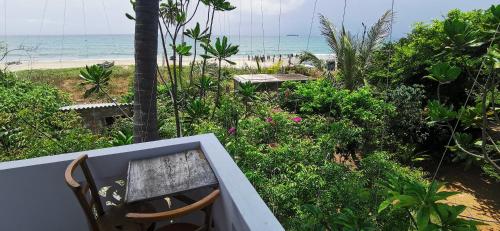 una silla sentada en un balcón con vistas a la playa en Blackstar Inn en Trincomalee