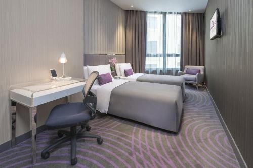 a hotel room with two beds and a desk at Silka Tsuen Wan, Hong Kong in Hong Kong