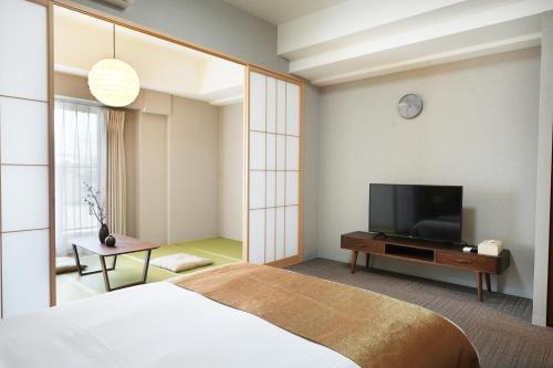 a bedroom with a bed and a flat screen tv at 川House道頓堀 in Osaka