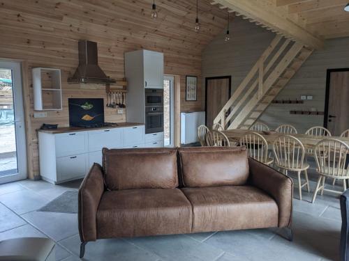 a living room with a brown couch in a kitchen at Cosy chalet in nature in Bastogne