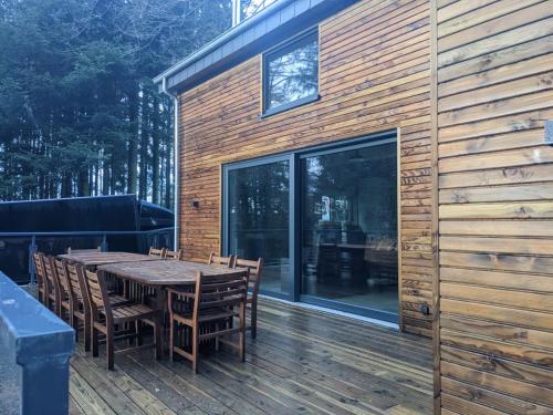 a wooden deck with a wooden table and chairs at Cosy chalet in nature in Bastogne