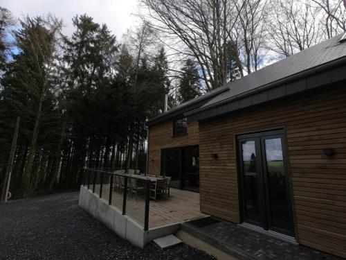 a wooden cabin with a deck and a table at Cosy chalet in nature in Bastogne