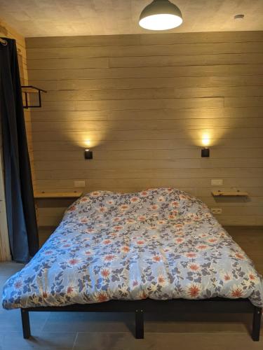 a bed with a comforter on it in a room at Cosy chalet in nature in Bastogne