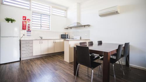a kitchen with a table and chairs and a refrigerator at Mounties @ Sussex in Sussex inlet