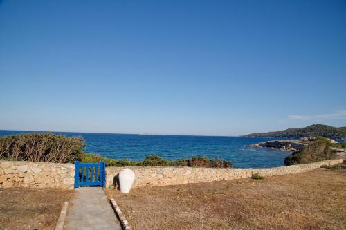 a blue bench sitting on a stone path next to the ocean at Aroura Homes 4BR Beachfront Villa in Spetses