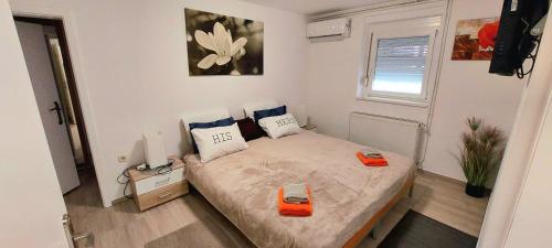 ein kleines Schlafzimmer mit einem Bett mit orangefarbenen Griffen in der Unterkunft JO-MA APARTMENT - SAFE parking and chrg station in Koseze