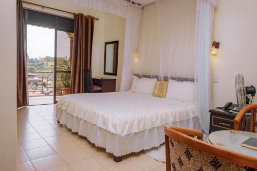 a bedroom with a white bed and a balcony at Tristar Hotel Kampala in Kampala