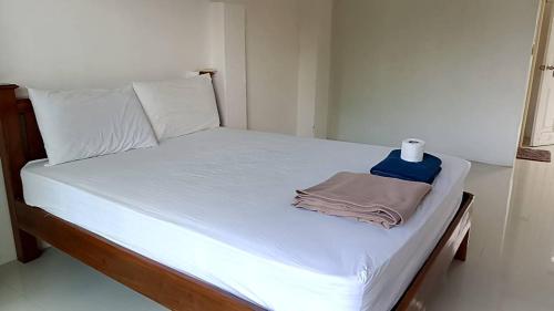 a bed with white sheets and a towel on it at Pranee Bungalow in Koh Tao