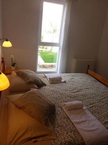 ein Schlafzimmer mit einem Bett mit Kissen und einem Fenster in der Unterkunft Comfortable Apartment Lavanda in Kornić