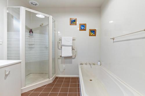 La salle de bains blanche est pourvue d'une baignoire et d'une douche. dans l'établissement Charming house with lovely views, à Queenstown