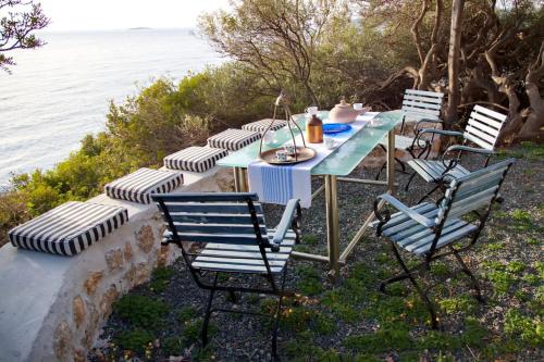 a table and chairs with the ocean in the background at Aroura Homes 4BR Beachfront Villa in Spetses
