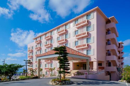 宮古島的住宿－海風珊瑚度假飯店，前面有棵树的粉红色建筑