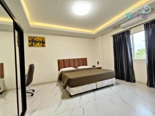 Schlafzimmer mit einem Bett, einem Schreibtisch und einem Fenster in der Unterkunft TY Holiday Resort in Pattaya