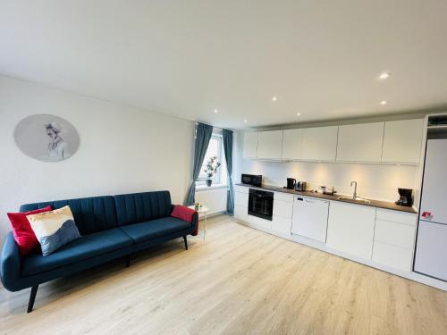 uma sala de estar com um sofá azul e uma cozinha em aday - Blue Sea apartment with balcony em Frederikshavn